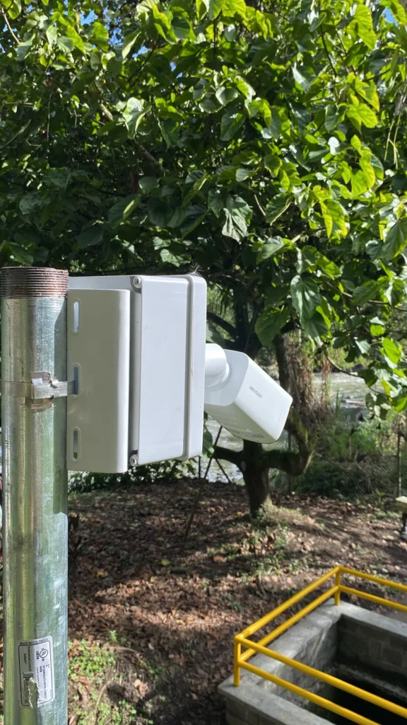 Cámara IP exterior instalada sobre poste junto a una bocatoma
