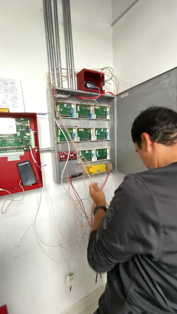 Técnico conectando módulos en el gabinete del sistema de incendios
